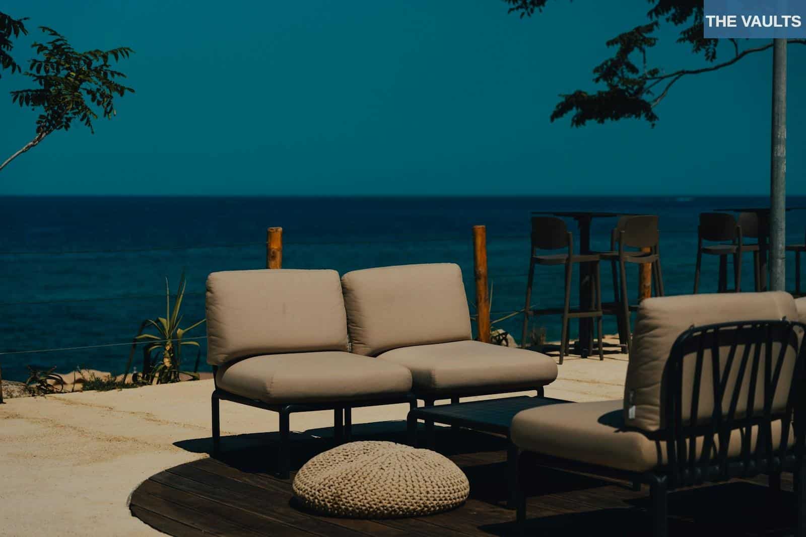 A couch and chair sitting on a patio next to the ocean
